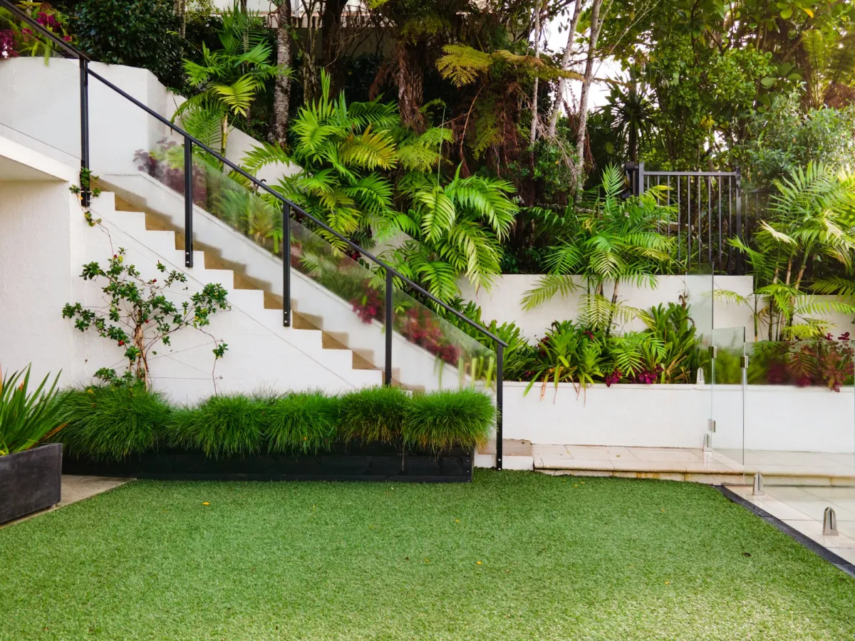 Taman rumah dengan rumput hijau dan tanaman tertata